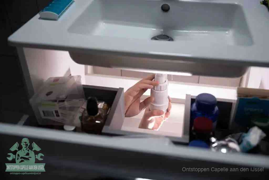 Een pompfles met zeep boven een wastafel, de heet water en afwasmiddel-methode om een vetprop in de afvoer los te maken in Capelle aan den IJssel