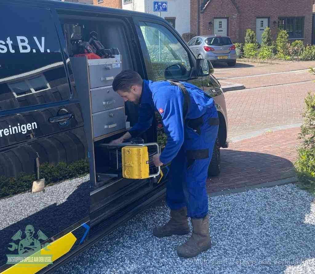 Een monteur pakt buiten op de oprit gereedschap uit de bedrijfsbus, het moment om een professional in te schakelen voor een verstopte afvoer in Capelle aan den IJssel