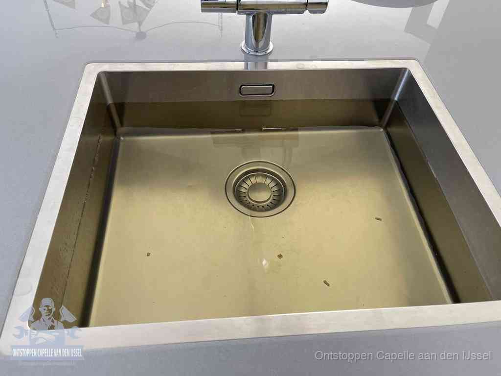 Stilstaand water in een rvs spoelbak dat niet wegloopt, een duidelijk signaal van een gootsteenverstopping in Capelle aan den IJssel