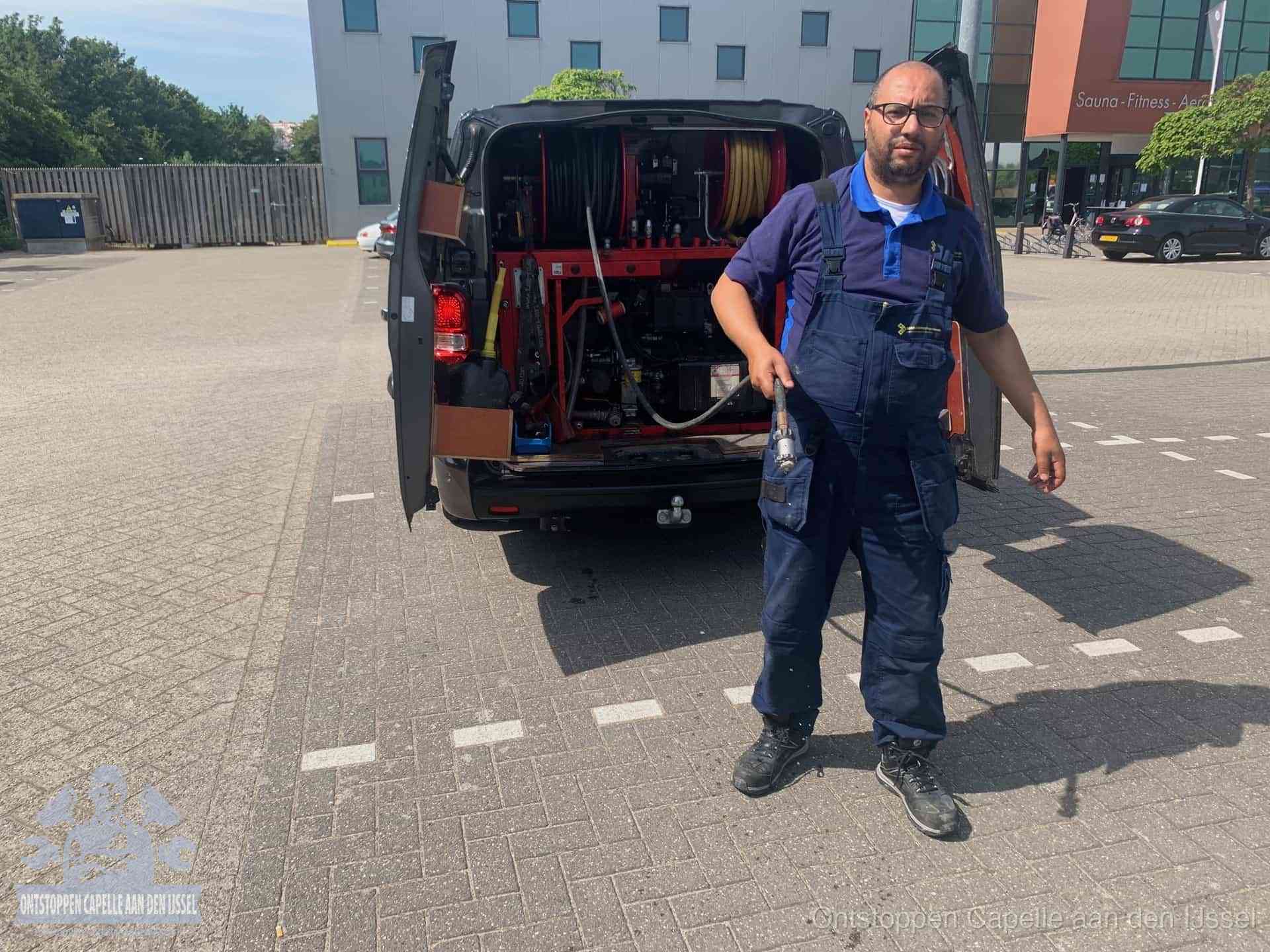 Een monteur bij zijn bestelbus met een hogedruk- en rioolreinigingsunit, klaar om de oorzaak van terugkerende wc-verstoppingen aan te pakken in Capelle aan den IJssel